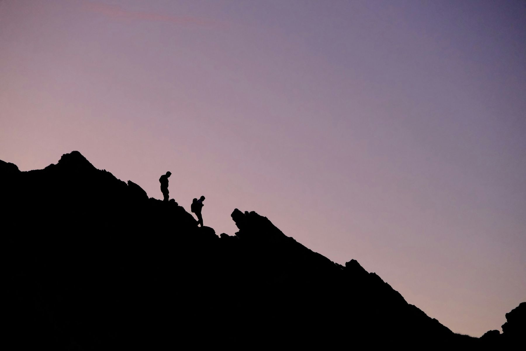 Two climbers descending a ridge at dusk